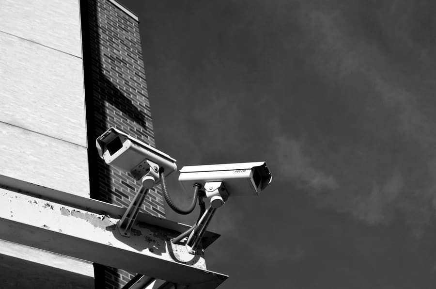 Two CCTV cameras on a bracket at the corner of a building